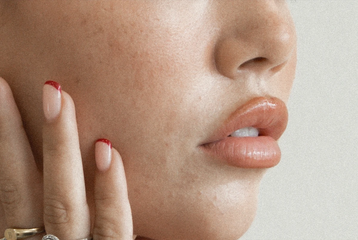 Close-up of a person's face, with hand touching cheek and lips slightly parted