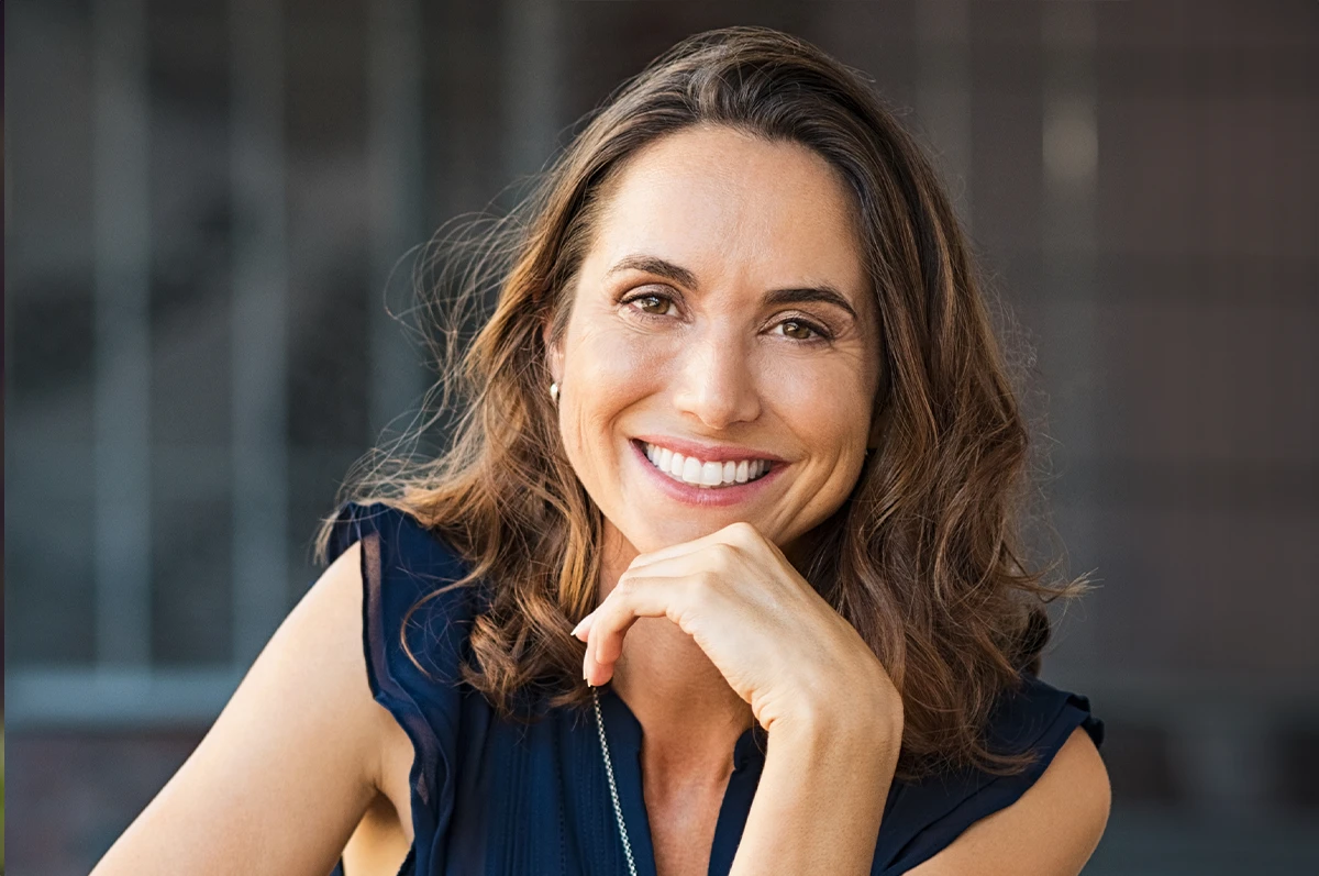 Smiling woman with wavy brown hair resting her chin on her hand