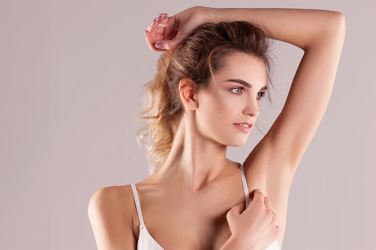 A woman with shoulder-length hair poses with one arm raised, looking to the side