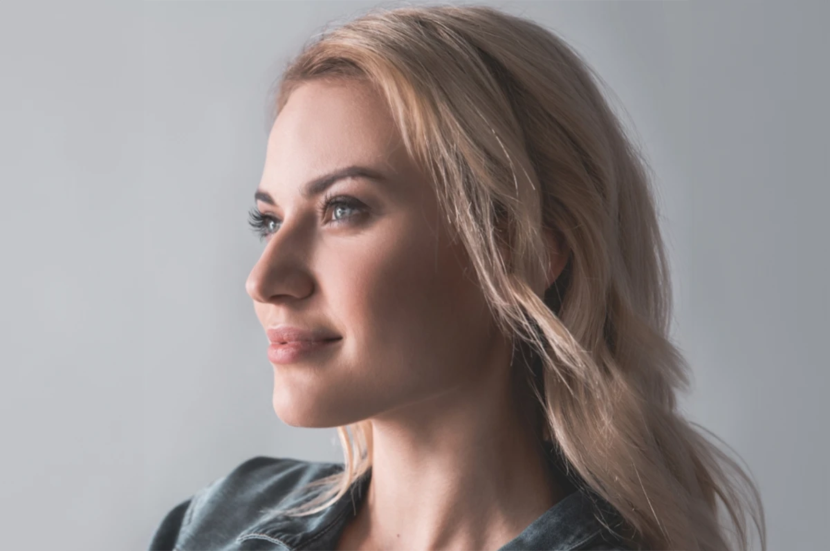 Woman with blonde hair looking to the side against a neutral background