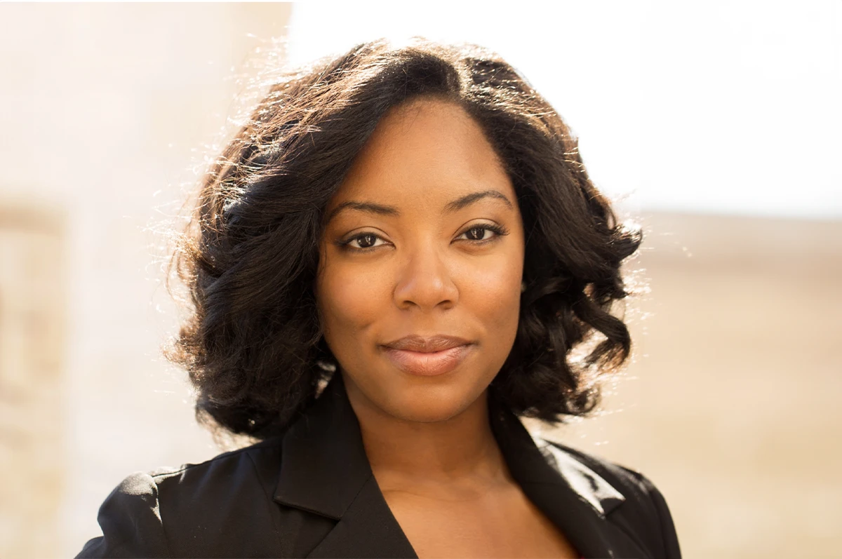 A woman with shoulder-length, curly hair looking directly at the camera
