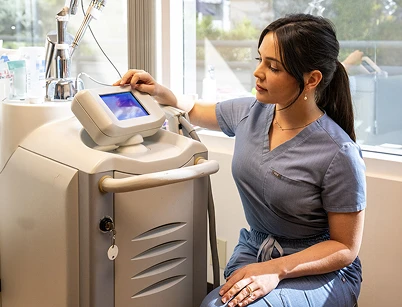 A person in scrubs interacts with a touchscreen on a medical device