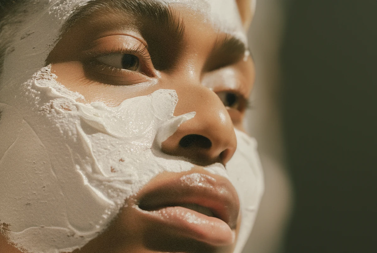 A close-up of a person’s face with a white cream mask applied