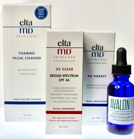 Three skincare product boxes and a blue dropper bottle on a reflective surface