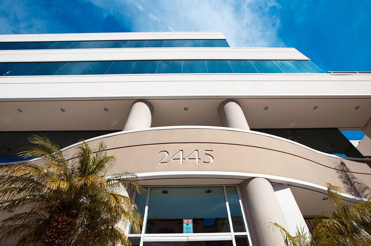 Modern building facade with columns and the number 2445 displayed. Blue sky above