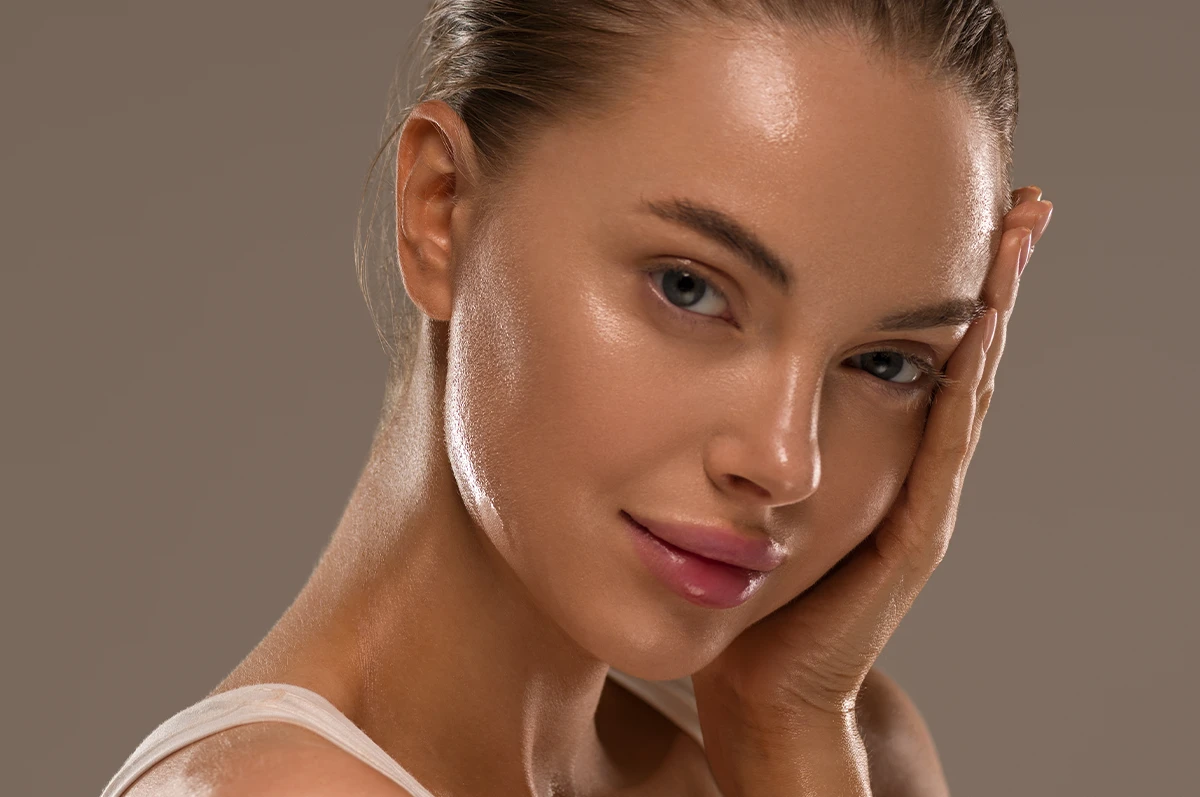 Close-up of a woman with smooth skin, touching her face and looking at the camera