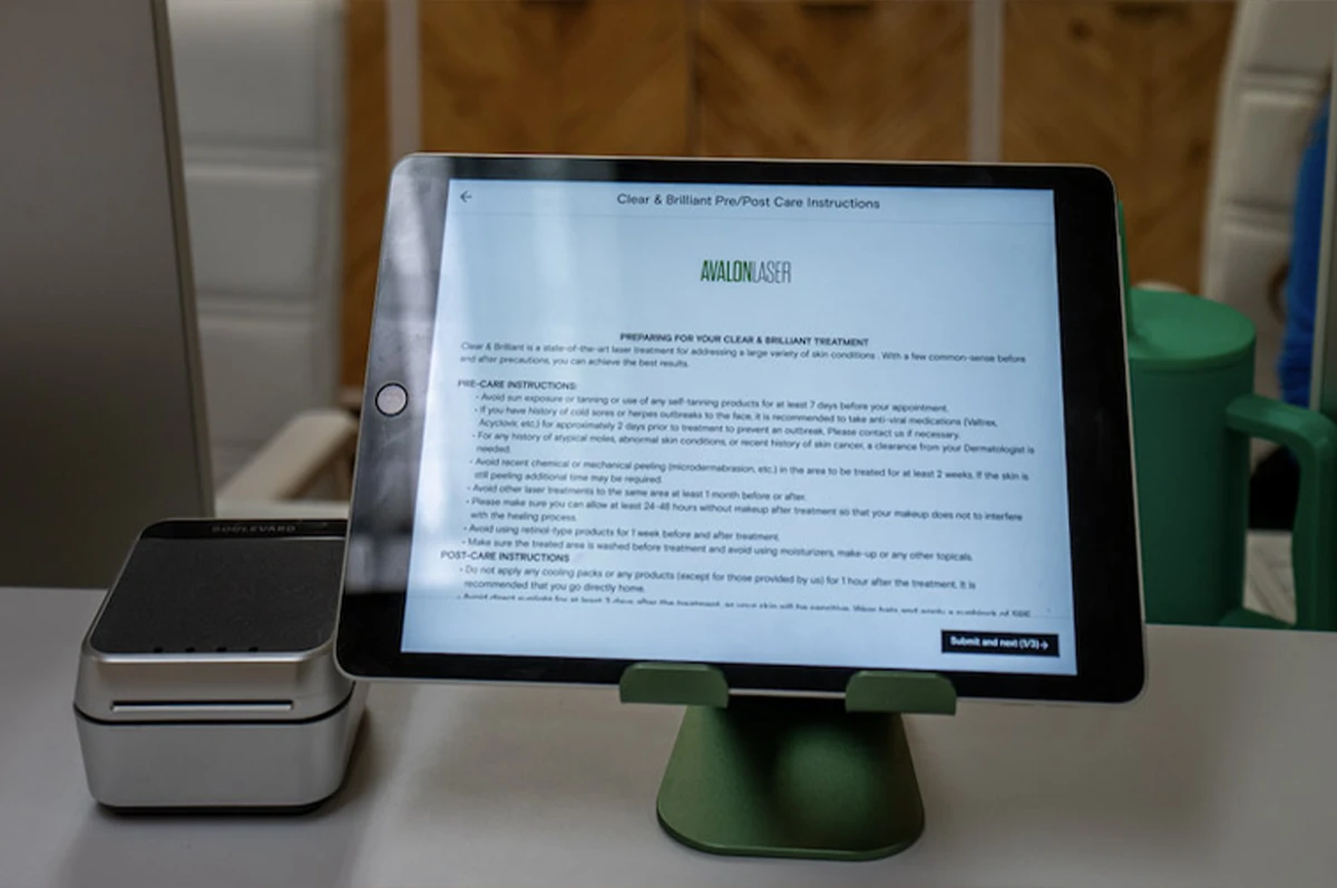 Tablet on a green stand displaying text, next to a small silver device