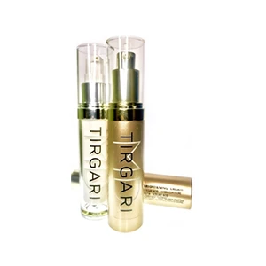 Two bottles of skincare serum with pumps, one gold and one clear, lying on a white surface