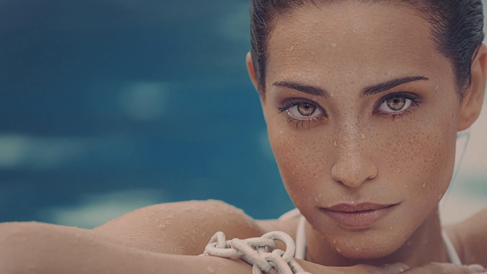 Close-up of a woman with wet hair and a serious expression, water background